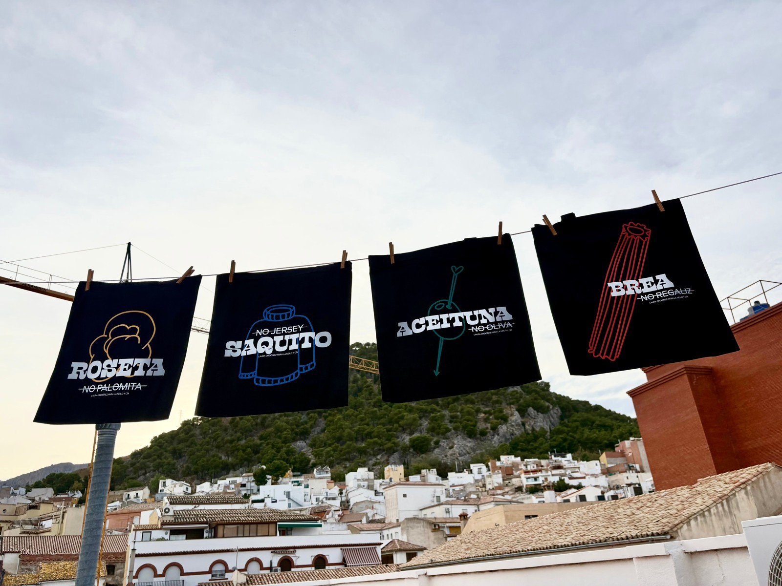 Las cuatro bolsas negras de la colección Arraigo tendidas en una cuerda: roseta, saquito, aceituna y brea