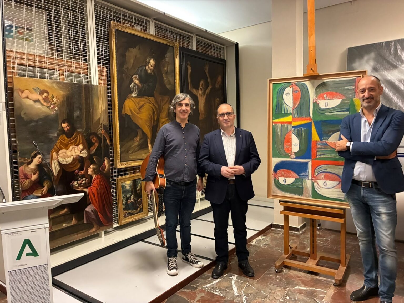 Presentación del ciclo de cantautores en el Museo de Jaén, con un músico con guitarra junto a los cuadros