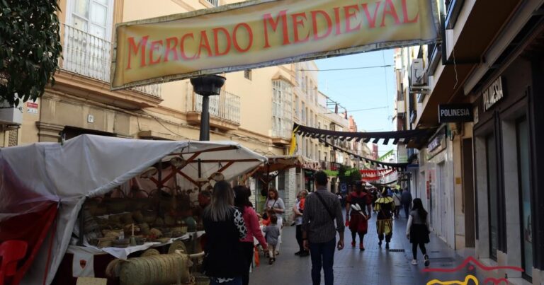 Ambiente de mercado medieval con puestos y figurantes