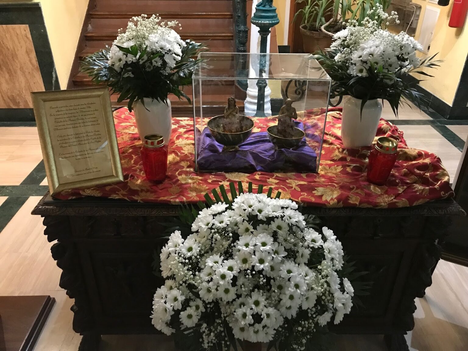 Tazones de ánimas de la antigua cofradía expuestos con flores blancas y velas en Villanueva del Arzobispo