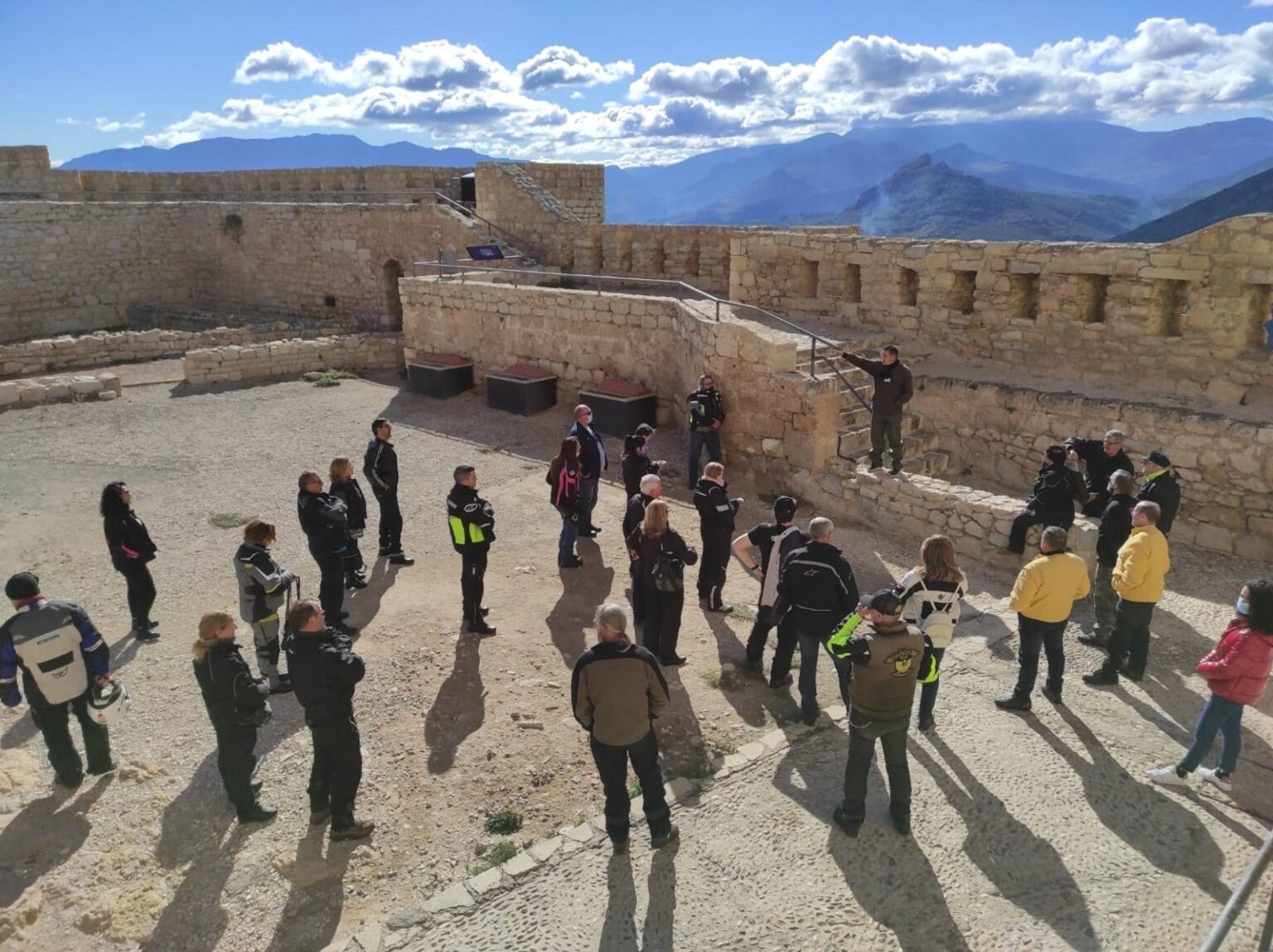 Grupo de visitantes en el patio de un castillo de la provincia de Jaén con la sierra al fondo